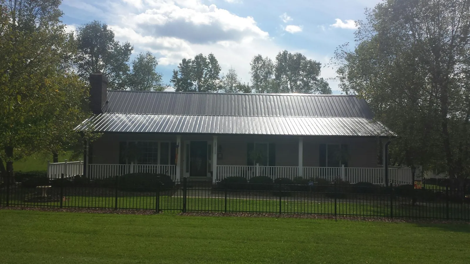 Gray metal roof on a brick ranch with a full width front porch — Gutter Guard Installation work by our crew in Berwick