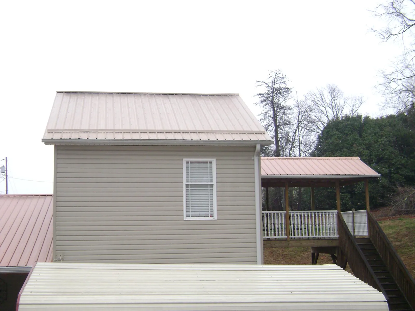 Tan metal roofs on a two story addition and attached porch, from a Roof Replacement job in Berwick